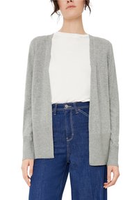 Cárdigan gris claro hecho de un suave tejido de punto, con diseño de frente abierto y puños acanalados, combinado con una camisa blanca y jeans azul oscuro.