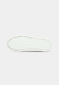 Witte rubberen zool met een gestructureerd patroon en gegolfde randen, met een gladde oppervlakte. Geen opvallende hardware of accenten zichtbaar.