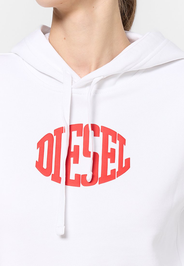 Haut à capuche blanc avec le texte courbé rouge "DIESEL" sur la poitrine, doté d'une capuche à cordons, porté par une personne montrée de la mentonnière aux épaules.
