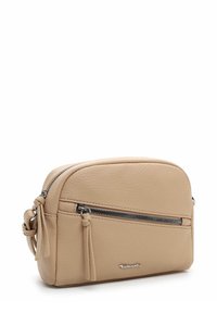 Beige leather crossbody bag with textured surface, rounded shape, front zip pocket, and decorative tassels. Silver-tone hardware accent.