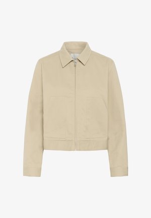 Veste beige à fermeture éclair avec deux poches avant, manches longues et col pointu, présentée sur fond blanc.