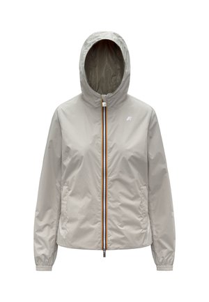 Giacca impermeabile color beige chiaro con cappuccio, cerniera frontale, polsini elastici, tasche laterali e piccolo logo sul petto a sinistra.
