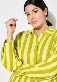 Camicia a righe verde e gialla, con colletto, maniche lunghe e tessuto testurizzato, caratterizzata da un fit rilassato e polsini con bottoni.
