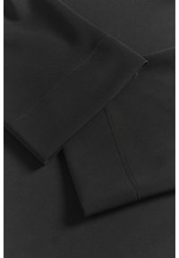 Černé sportovní legíny, hladká textura, přiléhavý design, viditelné švy na švech a elegantní, minimalistický vzhled. Prezentace na plocho.