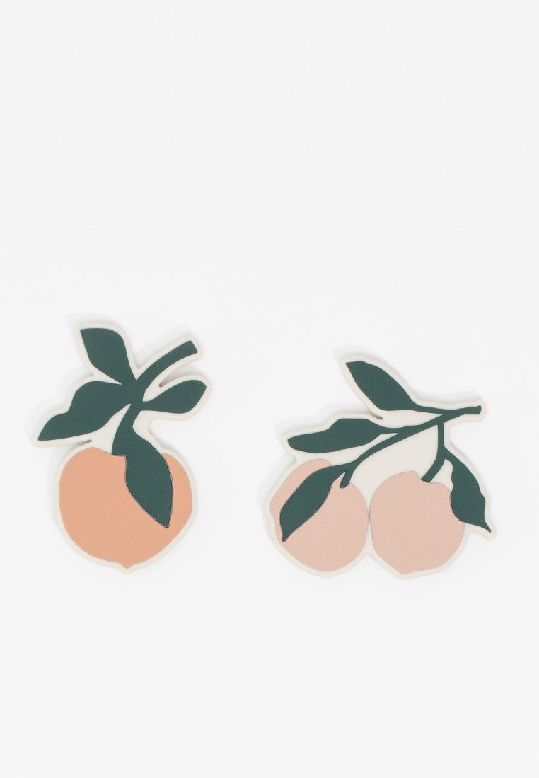 Deux sous-verres en silicone sur le thème des fruits : l'un est de couleur pêche avec une feuille vert foncé, et l'autre est rose avec deux feuilles sur un fond blanc.