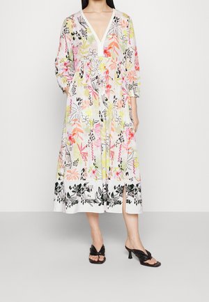 Blomstret kjole i letvægtsstof med V-hals, trekvartlange ærmer og lagdelt design. Detaljer inkluderer sorte accenter ved kanten.