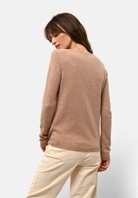Maglione a maglia marrone chiaro con una vestibilità morbida, scollatura a girocollo e maniche lunghe. Tessuto morbido e polsini a costine, abbinato a pantaloni color crema.
