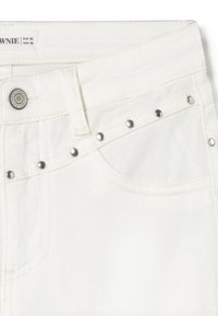 Jeans de mezclilla blanca con tachuelas plateadas en el borde del bolsillo frontal y un botón de metal etiquetado como "BROWNIE."
