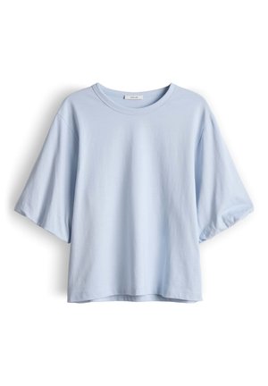 Lichtblauw, katoenen T-shirt met korte mouwen, losvallende pasvorm, ronde halslijn en een klein merklapje aan de binnenkant van de kraag.