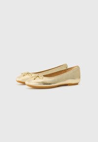 Gold ballet flats made of metallic leather. Features a rounded toe and a bow accent on the front. Smooth texture and flexible sole.