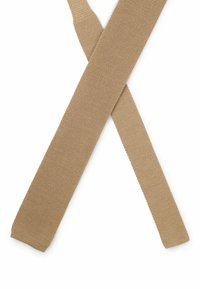 Beiger, gewebter Gürtel mit strukturierter Oberfläche, der zwei gleichmäßig geschnittene, gekreuzte Enden aufweist, die vor einem weißen Hintergrund eine "X"-Form bilden.