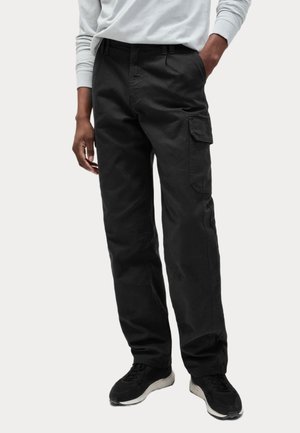 Black cargo pants made of durable fabric, featuring side pockets, a relaxed fit, and belt loops, paired with black sneakers.