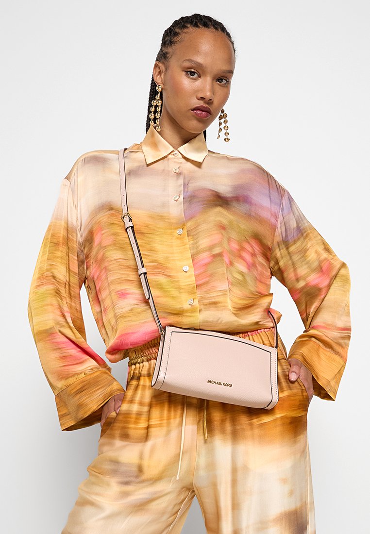 Roze leren schoudertas met een gestructureerde vorm, voorzien van een bovenste ritsluiting en een gegraveerd logo. De schouderband is verstelbaar voor extra gemak.