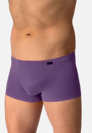 Männlicher Oberkörper, der lilafarbene enganliegende Boxershorts mit einem dezenten horizontalen Streifenmuster vor schlichtem Hintergrund trägt.