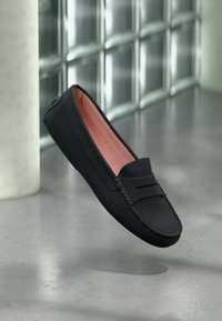 Černé kožené mokasíny s prošíváním, hladkým povrchem a kontrastním růžovým interiérem; mají klasický design na obouvání.
