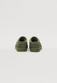 Chaussures en daim vert avec profil bas, bout arrondi et coutures texturées contrastantes le long du col. Semelle en caoutchouc plate.