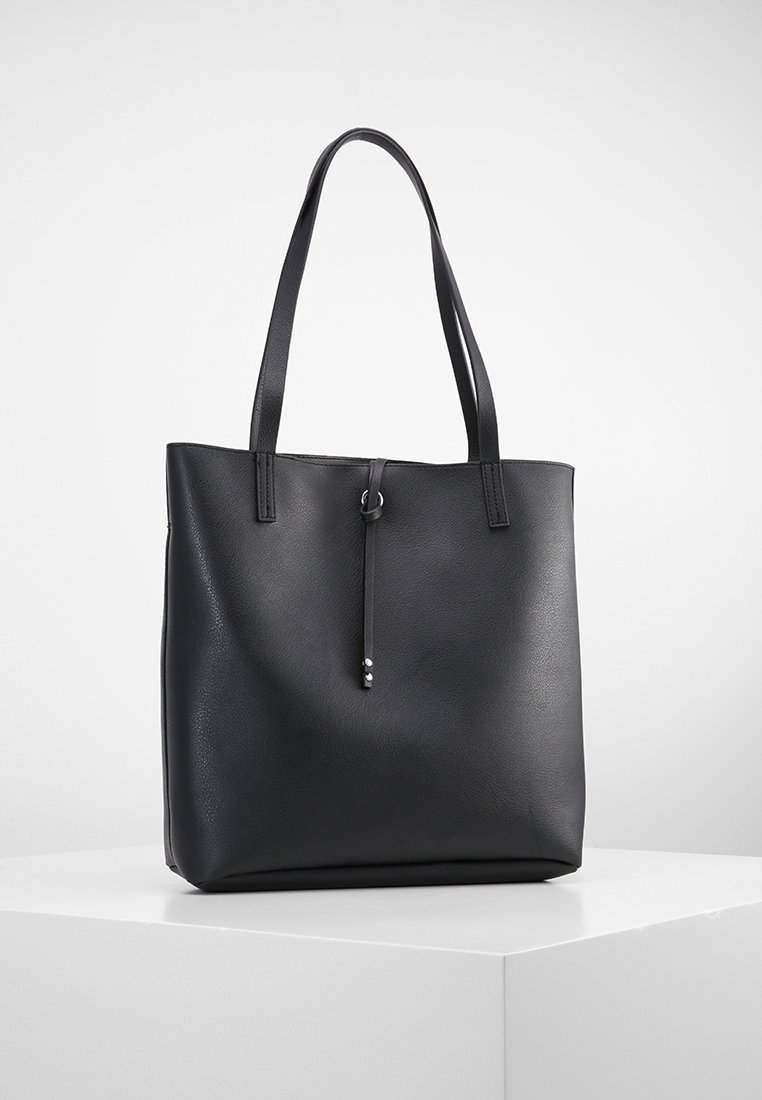 Czarna torba typu tote wykonana z teksturowanego syntetycznego materiału, z dwoma uchwytami na ramię oraz ozdobnym skórzanym trokiem z metalowymi detalami.