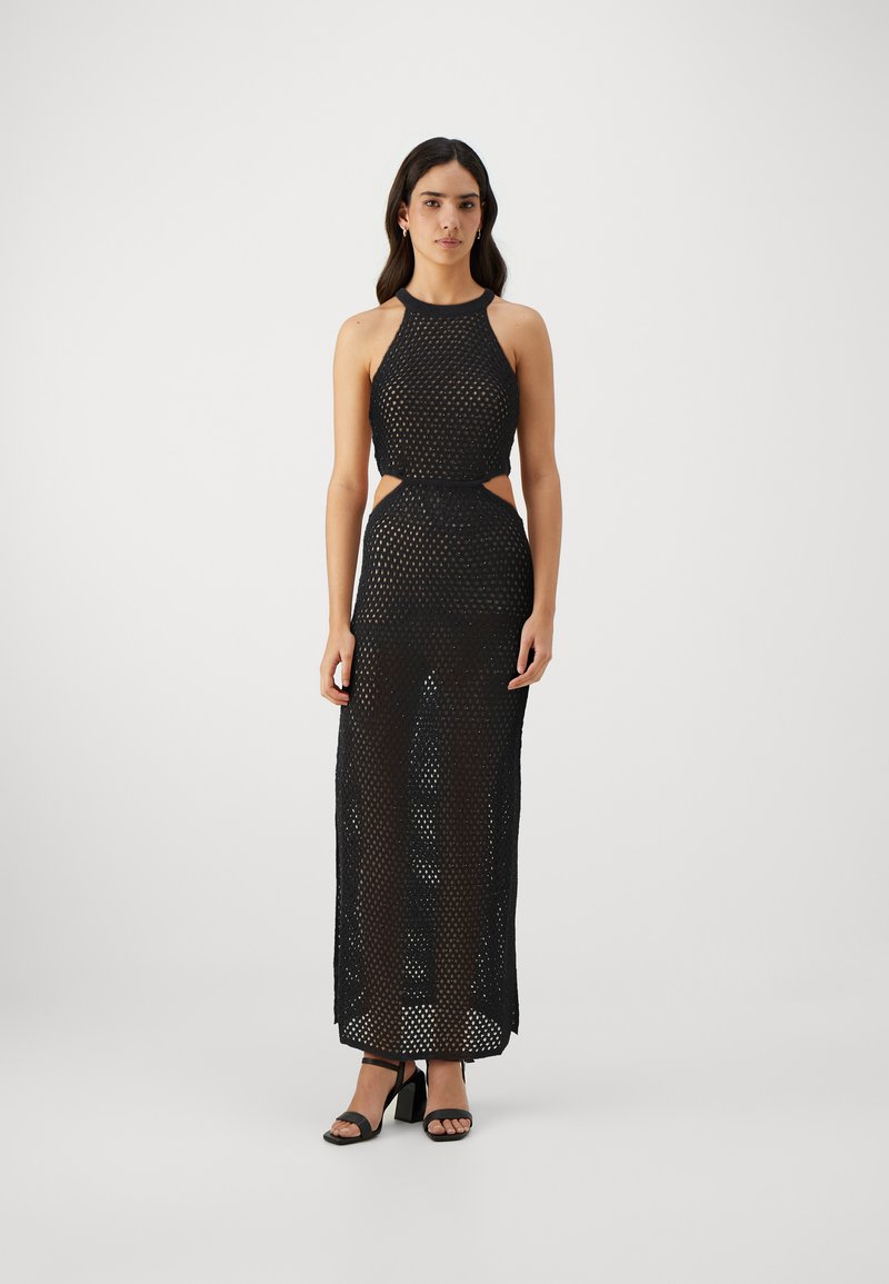 Robe en maille noire avec col halter, taille découpée et longueur de sol. Tissu texturé et apparence transparente avec un matériel minimal.