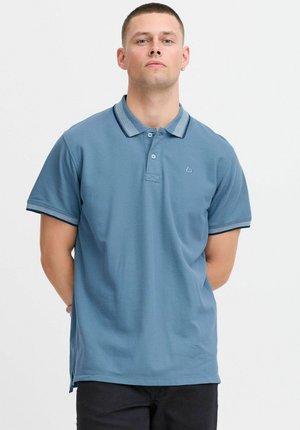 Polo skjorte i dæmpet blå med en tekstureret stof, kontrasterende krave og manchetter i lys blå og mørk marineblå, med et lille logo.