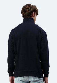 Marineblaues Kapuzensweatshirt mit hohem Kragen und langen Ärmeln. Mit gerippten Bündchen und lockerer Passform, aus weichem Material gefertigt.