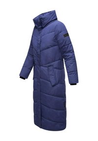 Cappotto lungo e voluminoso di un blu profondo con cuciture diagonali, collo alto, tasche laterali e dettagli neri sulla manica. Materiale leggero.