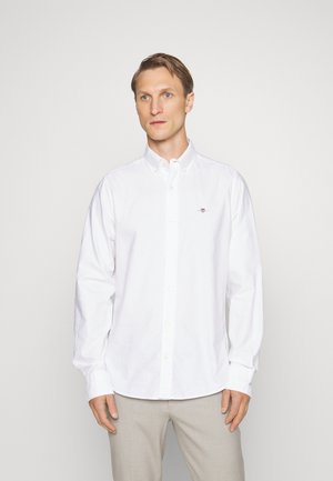 Witte button-up shirt van katoen. Kenmerkt zich door een klassieke kraag, lange mouwen en een klein geborduurd logo op de borst. Zijdezachte textuur.