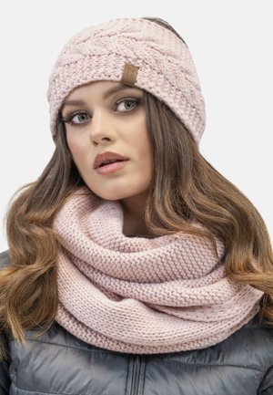 Bonnet rose en tricot avec un motif en câble et une étiquette en cuir, assorti à une écharpe infini rose au design texturé.