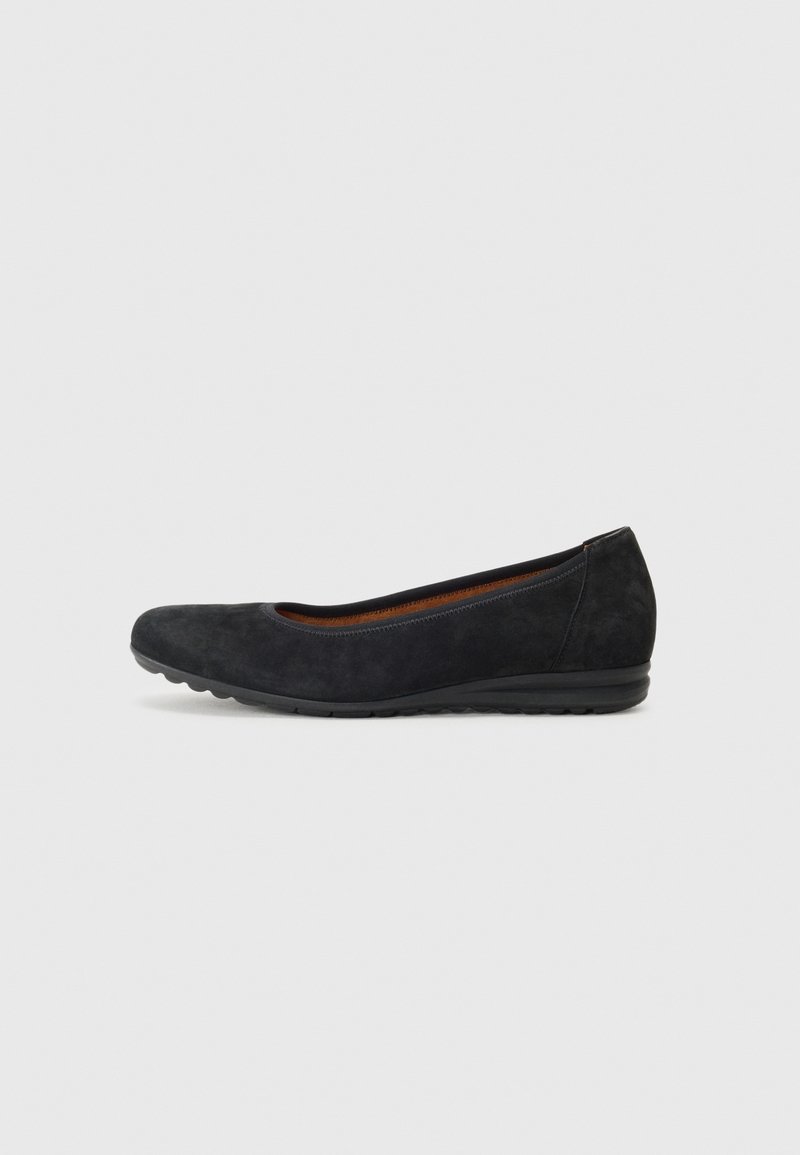 Chaussure plate en daim noir avec bout arrondi et semelle en caoutchouc basse, présentée sur un fond gris clair.