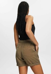 Khaki-shortsit, joissa on rento istuvuus, joustava vyötärönauha, käännetyt lahkeet ja takataskut. Kangas näyttää sileältä ja mattaiseltä.