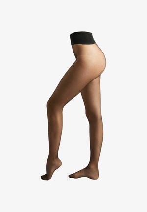 Collants noirs transparents portés sur des jambes féminines, un pied à plat et l'autre légèrement relevé sur la pointe, sur un fond blanc.