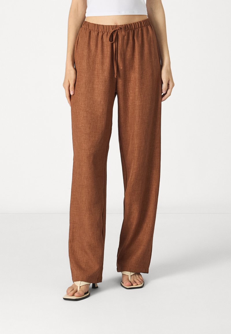 Pantalons en lin marron à jambes larges avec une taille élastique et cordon de serrage. Texture lisse et coupe décontractée, appropriés pour une tenue casual.