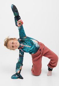 Farverig jumpsuit med blomsterprint i teal med pink detaljer, parret med fluffy, pink sweatpants og sorte boots.