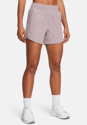 Osoba nosząca jasnofioletowe sportowe szorty, białe skarpetki za kostkę i białe buty do biegania, stojąca z rękami swobodnie zwisającymi obok ud.