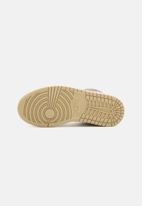 Sole di sneaker Nike in gomma beige con motivi circolari e a spina di pesce. Superficie testurizzata con un dettaglio del logo circolare.