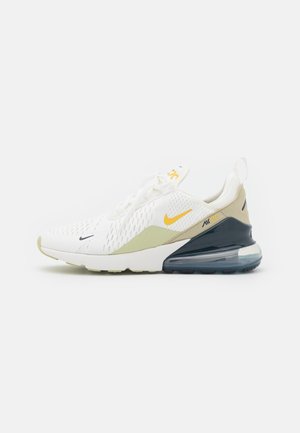 Baskets Nike Air Max 270 blanches et beiges avec swoosh jaune et semelle coussin d'air noire visible, vue de côté sur fond blanc.