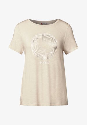 Camiseta beige de manga corta con un diseño gráfico circular plateado con líneas radiales y la palabra "SOLEIL" debajo del gráfico. Textura suave.