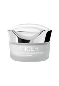 Lancer Gravity Defying Moisturizer in einem frosted grauen Glas mit einem silbernen, geschwungenen Deckel. Auf dem Glas steht der Produktname und "mit Firmungskomplex."