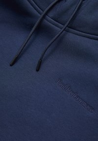 Felpa blu marina realizzata in morbido tessuto con una trama intrecciata, coulisse regolabile e logo "PeakPerformance" ricamato sul davanti.