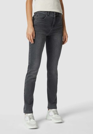 Dunkelgraue enge Jeans mit glatter Textur, ausgestattet mit einem klassischen Fünf-Taschen-Design und dezentem Nähen, kombiniert mit weißen Sneakern.