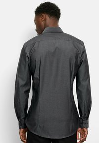 Donkergrijze longsleeve shirt met een textuurpatroon, slim fit ontwerp, met knoopmanchetten en een standaard kraag. Zichtbare naaddetails aan de achterkant.