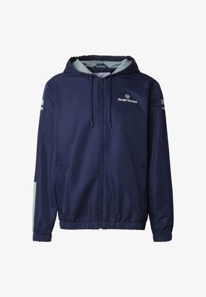 Tamsiai mėlynas užtraukiamas gobtuvu džemperis su šviesiai pilku vidiniu gobtuvo pamušalu, elastingais rankogaliais, šoninėmis kišenėmis ir baltu Sergio Tacchini logotipu ant krūtinės.