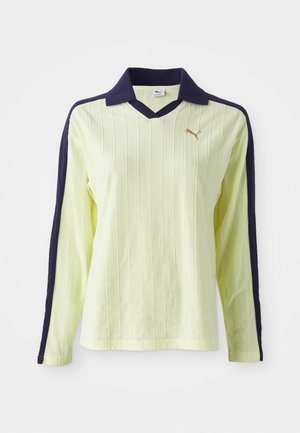 Light yellow long-sleeve polo with a dark blue collar and sleeves. Features a textured ribbed design and a small gold logo on the chest.