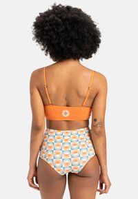 Korkeavyötäröinen bikinit, joissa on oranssi yläosa ja kuvioidut alaosat, joissa on aurinkosateen muotoisia kuvioita oranssina ja tealina. Pehmeää ja joustavaa kangasta.