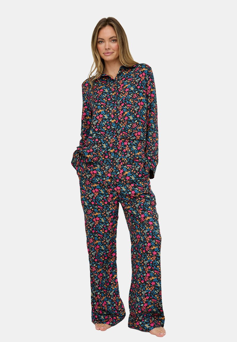 Floraler Pyjama-Set mit dunklem Hintergrund und Blumen in Pink, Blau und Grün. Locker sitzend, mit langen Ärmeln und Taschen an der Hose.