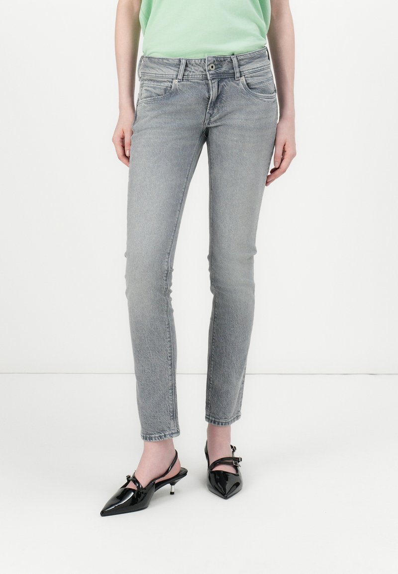 Sive jeans skinny iz petimi žepi, zbledela tekstura in gumbasto zapiranje. V kombinaciji s črnimi lakastimi čevlji s konicami.