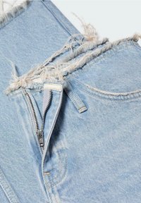 Jasnoniebieskie dżinsy z postrzępionymi brzegami, zamkiem błyskawicznym z przodu i standardowymi kieszeniami. Materiał wykazuje subtelne wyblaknięcie i różnorodne detale przeszycia.