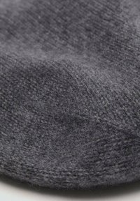 Tessuto grigio lavorato a maglia con una texture morbida, caratterizzato da un motivo sottile e una superficie leggermente pelosa, che indica calore e comfort.