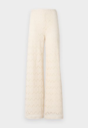 Pantaloni larghi color crema realizzati in pizzo con un motivo geometrico. Caratterizzati da una vita alta e una silhouette fluida.