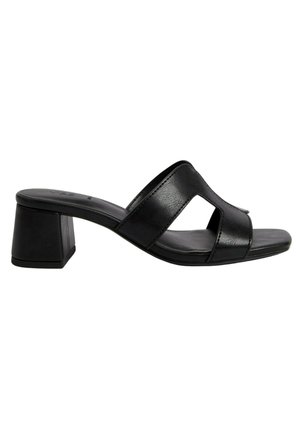 Mules de cuero negro con tacón bloque y diseño de punta abierta, con una cinta ancha que presenta un detalle recortado. Textura suave, estilo minimalista.
