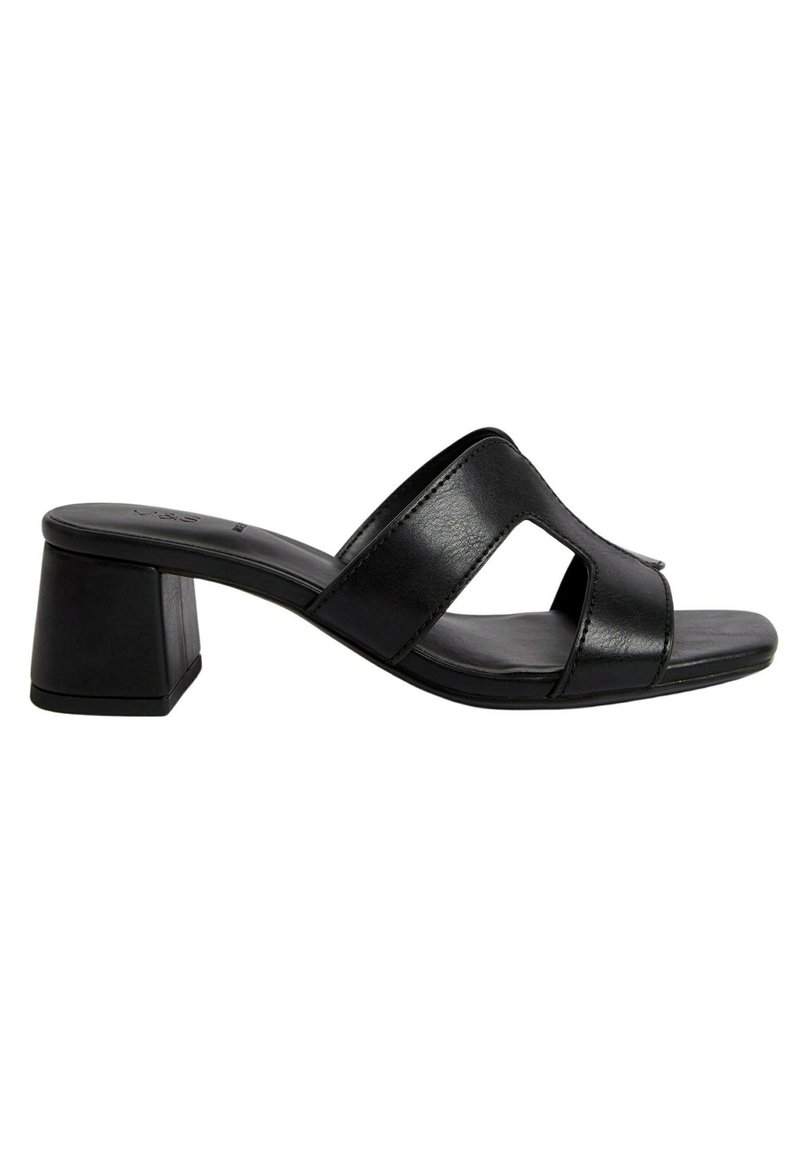 Mules de cuero negro con tacón bloque y diseño de punta abierta, con una cinta ancha que presenta un detalle recortado. Textura suave, estilo minimalista.
